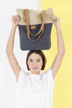 Kwooksta soft jute classic tote in grey and natural balancing on model's head with adjustable eco leather shoulder straps