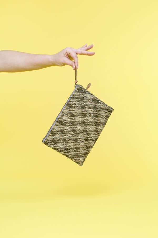 Kwooksta herringbone jute clutch pouch in green with eco leather wrist strap in hand