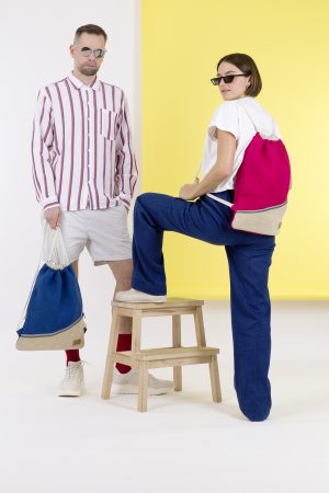 Kwooksta soft jute drawstring bag in red and blue carried by male and female models