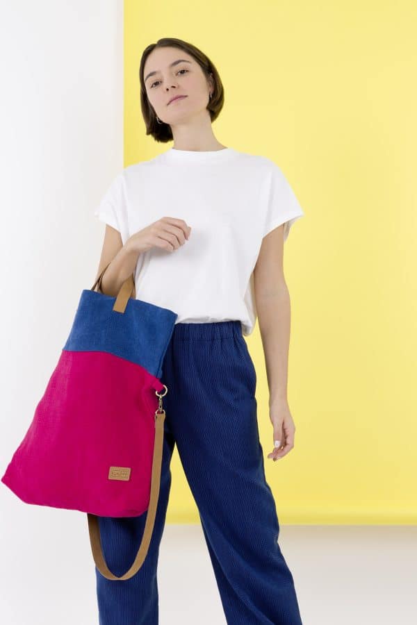 Kwooksta soft jute foldable tote bag in red and blue carried over the forearm by model using eco leather handles