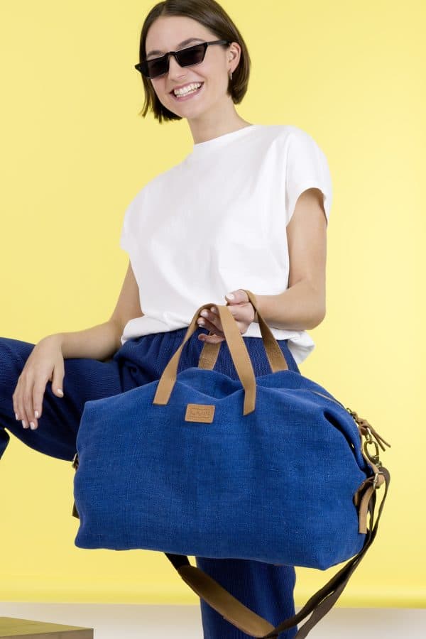 Kwooksta soft jute little weekender bag in blue carried in hand with eco leather handles by female model
