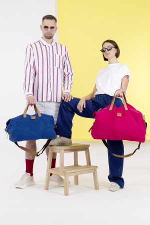 Kwooksta Soft Jute große und kleine Weekender Taschen in Blau und Rot getragen von männlichem und weiblichem Model.